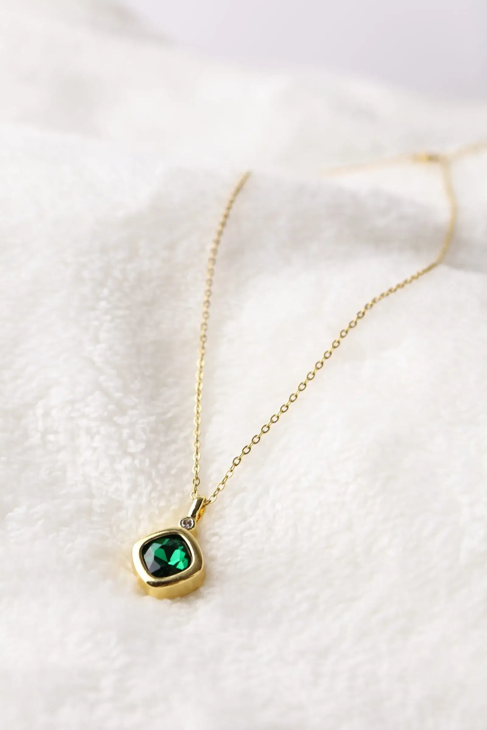 A diamond-shaped chain with a green zirconium bead